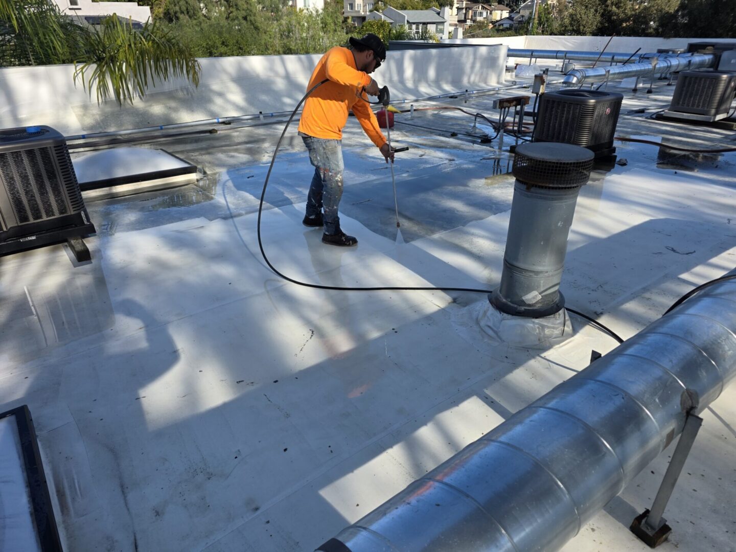 Roofer sealing flat commercial roof near vents