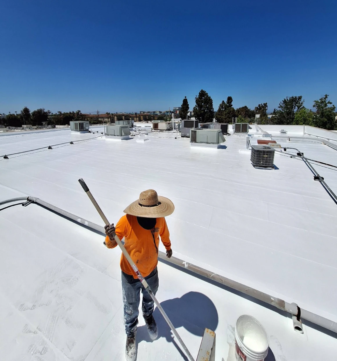 Person coating roof with reflective paint